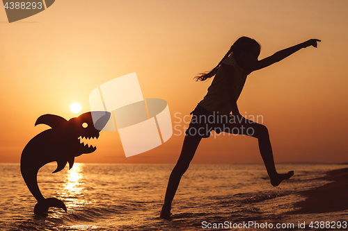 Image of One happy little girl playing on the beach at the sunset time.