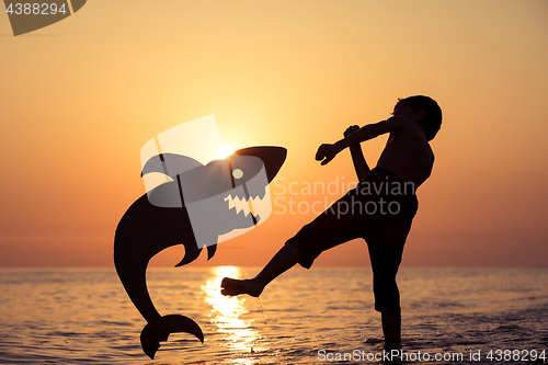 Image of One happy little boy playing on the beach at the sunset time.