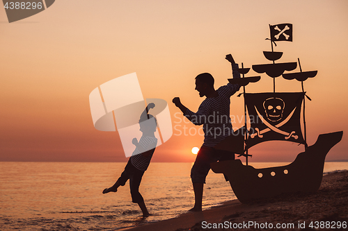 Image of Father and son  playing on the beach at the sunset time.