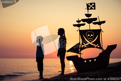 Image of Happy children playing on the beach at the sunset time.