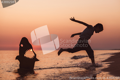 Image of One happy little boy playing on the beach at the sunset time.