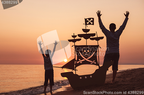 Image of Father and son  playing on the beach at the sunset time.