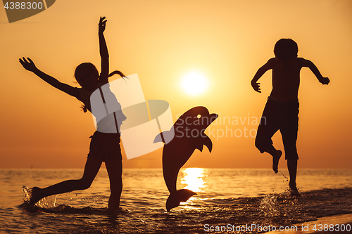 Image of Happy children playing on the beach at the sunset time.