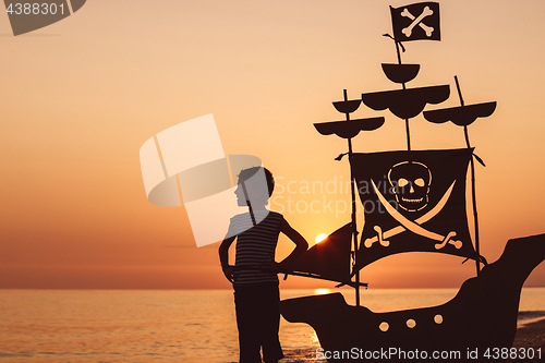 Image of One happy little boy playing on the beach at the sunset time.