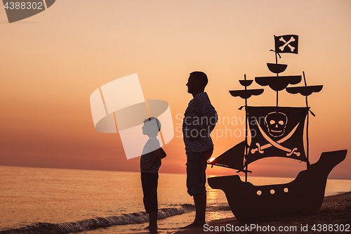 Image of Father and son  playing on the beach at the sunset time.