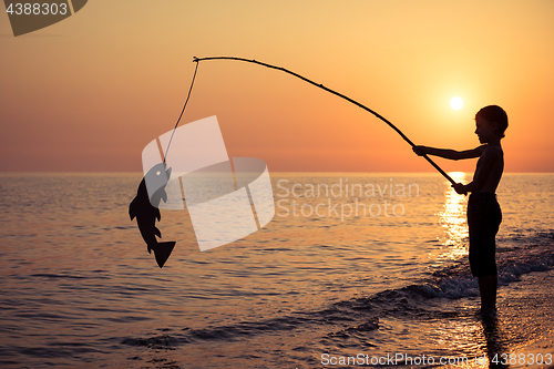 Image of One happy little boy playing on the beach at the sunset time.