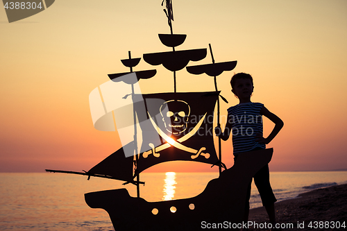 Image of One happy little boy playing on the beach at the sunset time.