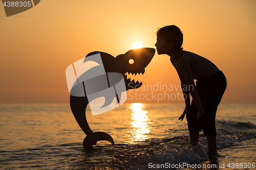 Image of One happy little boy playing on the beach at the sunset time.