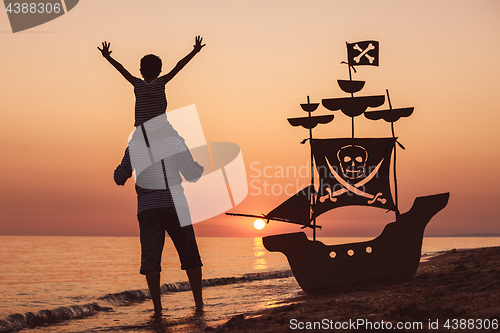 Image of Father and son  playing on the beach at the sunset time.