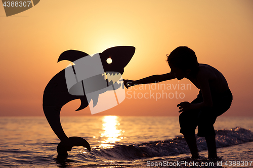 Image of One happy little boy playing on the beach at the sunset time.