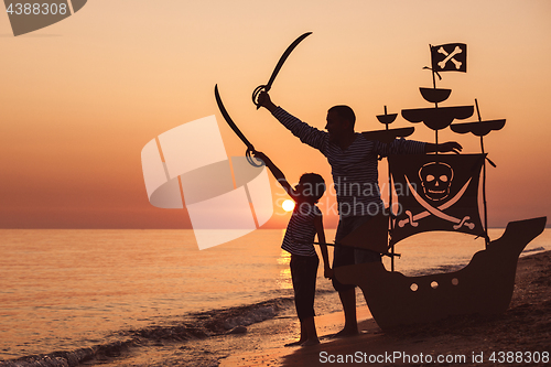 Image of Father and son  playing on the beach at the sunset time.