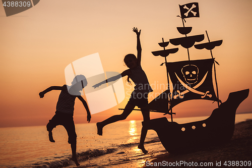 Image of Happy children playing on the beach at the sunset time.