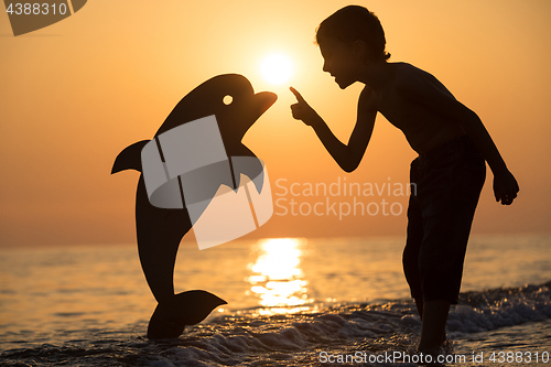 Image of One happy little boy playing on the beach at the sunset time.