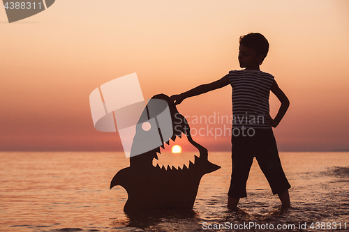 Image of One happy little boy playing on the beach at the sunset time.