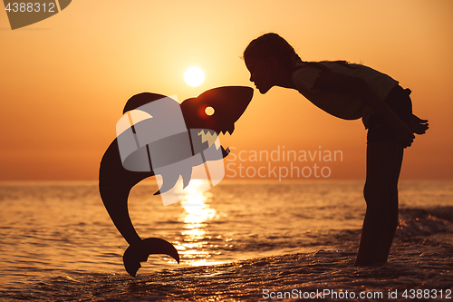 Image of One happy little girl playing on the beach at the sunset time.