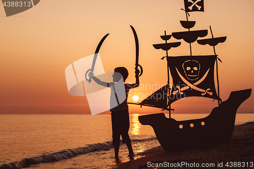 Image of One happy little boy playing on the beach at the sunset time.