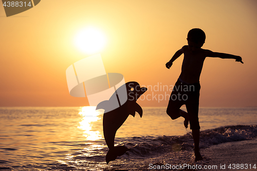 Image of One happy little boy playing on the beach at the sunset time.