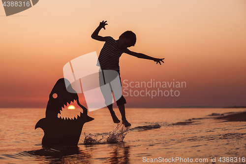 Image of One happy little boy playing on the beach at the sunset time.