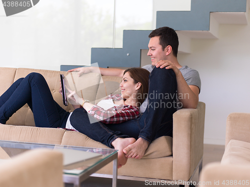 Image of couple relaxing at  home with tablet computers