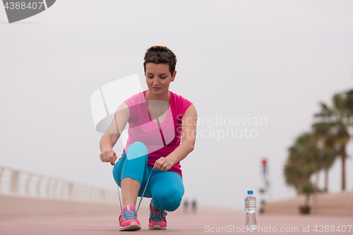 Image of Young woman tying shoelaces on sneakers