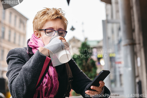 Image of Woman drinking coffee with smartphone