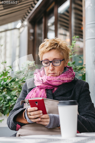 Image of Smiling woman with phone in cafe