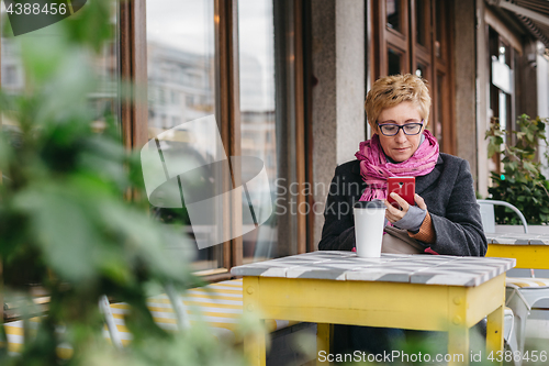 Image of Woman with drink and smartphone