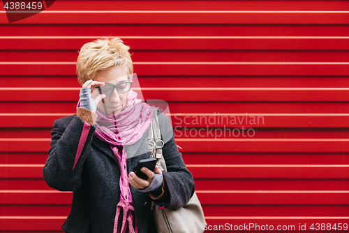 Image of Adult woman with smartphone on street