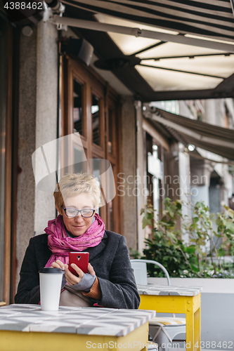 Image of Woman with drink and smartphone