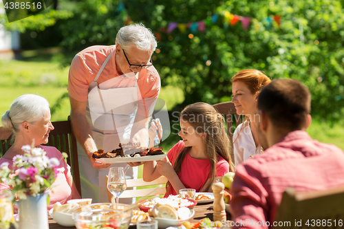 Image of family having dinner or barbecue at summer garden