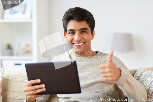 Image of man with tablet pc showing thumbs up at home