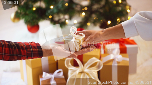 Image of close up of couple hands with christmas gift box