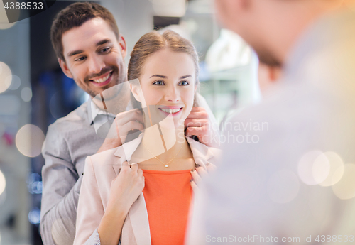 Image of couple trying golden pendant on at jewelry store