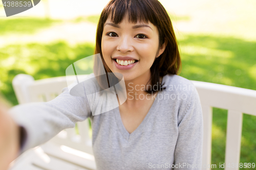 Image of happy smiling asian woman taking selfie at park