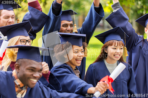 Image of happy students in mortar boards with diplomas