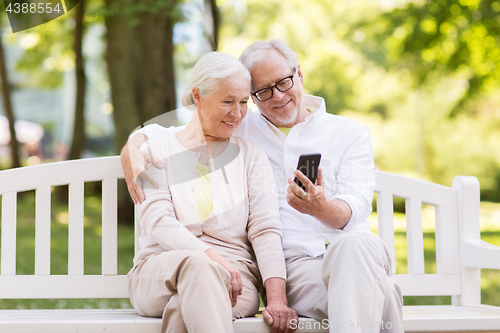 Image of happy senior couple with smartphone at park