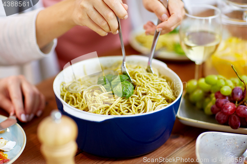 Image of pasta with basil in bowl and other food on table