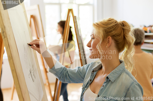 Image of woman with easel drawing at art school studio