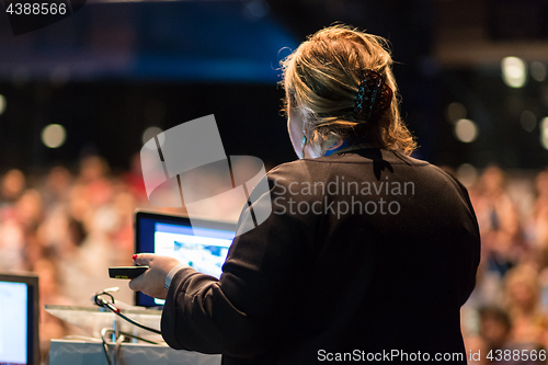 Image of Female public speaker giving talk at Business Event.