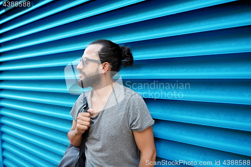 Image of man in sunglasses with bag standing at street wall