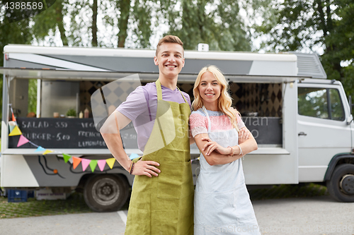 Image of happy couple of young sellers at food truck