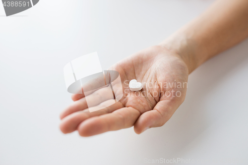 Image of close up of hand holding medicine heart pill