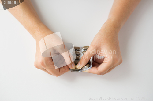 Image of woman hands opening pack of medicine pills