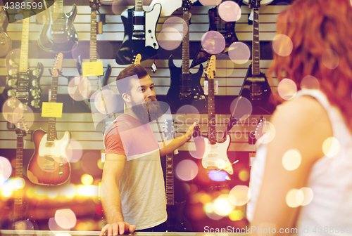 Image of assistant showing customer guitar at music store