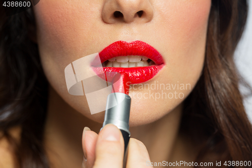 Image of close up of woman applying red lipstick to lips