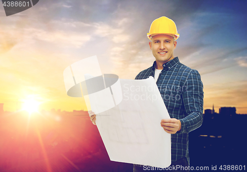 Image of male builder in yellow hard hat with blueprint