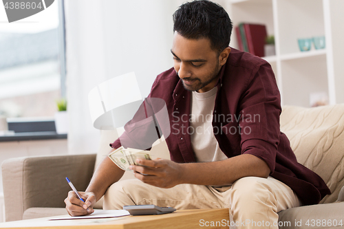 Image of man with money and calculator filling papers