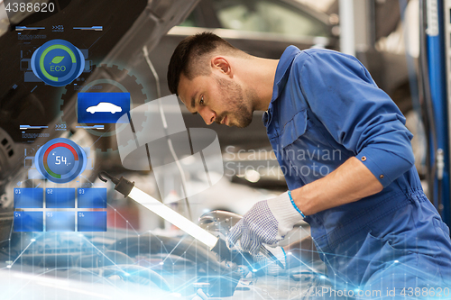 Image of mechanic man with lamp repairing car at workshop