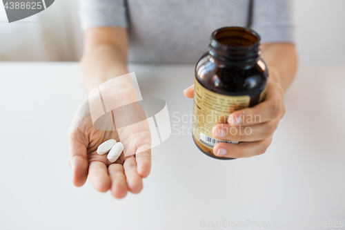 Image of close up of hands holding medicine pills and jar