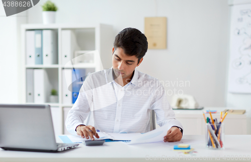 Image of businessman with papers and calculator at office